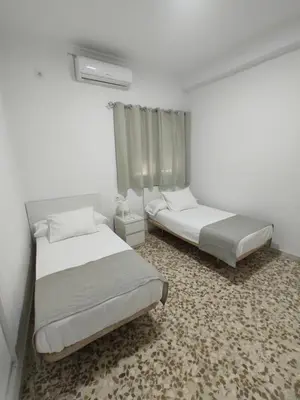 two beds in a small room with white walls at Hostal Mellizo in Lebrija