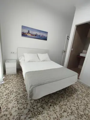 a bedroom with a bed with a picture on the wall at Hostal Mellizo in Lebrija