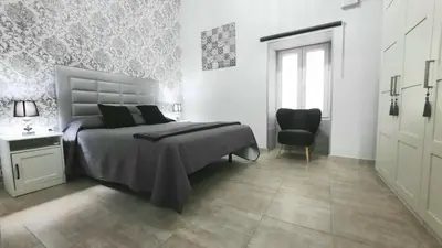 a white bedroom with a bed and a chair at Apartamento Levante in Cádiz