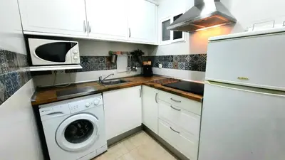 a kitchen with white cabinets and a washer and dryer at Apartamento Levante in Cádiz