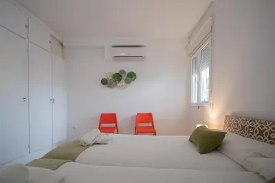 a bedroom with two beds and two red chairs at Apartamento Malibu Cadiz playa in Cádiz