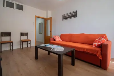 a living room with an orange couch and a coffee table at Apartamento Malibu Cadiz playa in Cádiz
