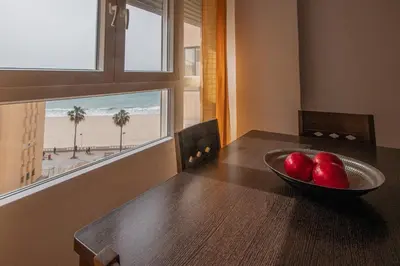 a bowl of apples on a wooden table with a view of the beach at Apartamento Malibu Cadiz playa in Cádiz