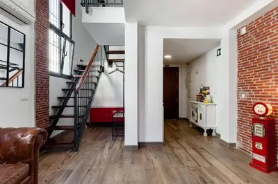 a living room with a staircase and a brick wall at SH El Teatro. Dúplex industrial en el Falla. in Cádiz