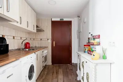 a kitchen with white cabinets and a washer and dryer at SH El Teatro. Dúplex industrial en el Falla. in Cádiz