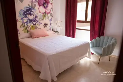 a bedroom with a bed with a pink pillow and a chair at Apartamento Pale Cream MRZ Rentals in Jerez de la Frontera