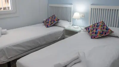two beds in a small room with a lamp on a table at Apartamento Amanecer Cadiz in Cádiz