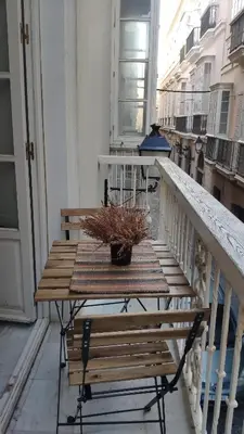 a wooden table on a balcony with a potted plant at Apartamento El Gaditano Errante in Cádiz
