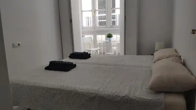 a white bedroom with a bed with two pillows on it at Apartamento El Gaditano Errante in Cádiz
