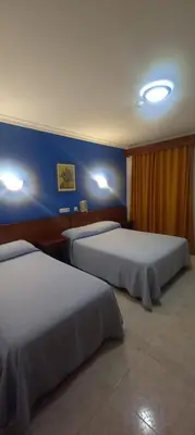 a hotel room with two beds and a blue wall at El Faisan C&R Hotel in Arcos de la Frontera