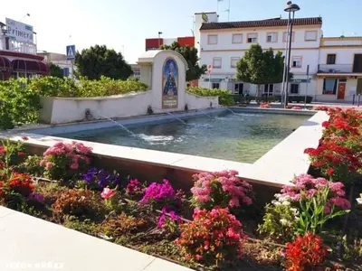 a fountain in the middle of a garden with flowers at El Faisan C&R Hotel in Arcos de la Frontera