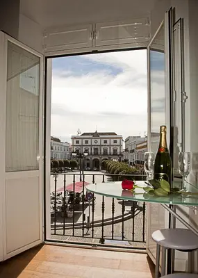 a glass table with a bottle of wine on a balcony at Apartamentos La Casa de la Alameda in Medina Sidonia