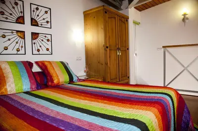 a bedroom with a colorful striped bed with a wooden cabinet at Apartamentos La Casa de la Alameda in Medina Sidonia