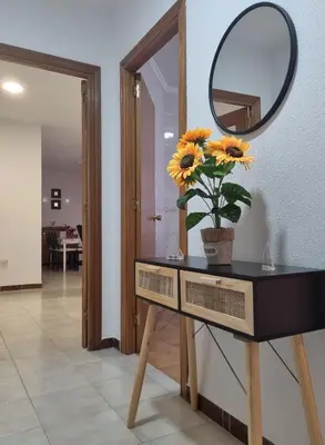 a table with a mirror and a vase with sunflowers on it at Apartamento Cayetano in Rota