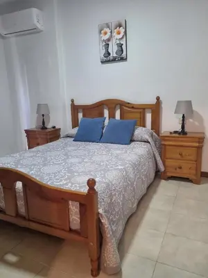 a bedroom with a wooden bed with blue pillows at Apartamento Cayetano in Rota