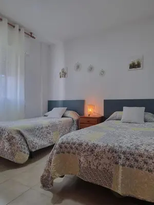a bedroom with two beds and a table with a lamp at Apartamento Cayetano in Rota