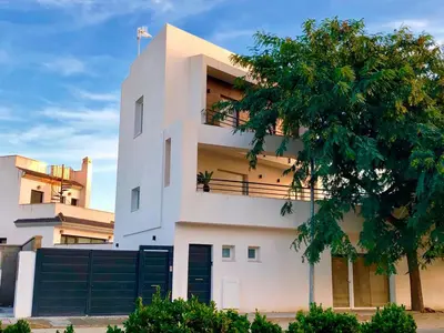 a white building with a tree in front of it at Vivienda Avenida de la Manzanilla in Sanlúcar de Barrameda