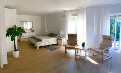 a bedroom with a bed and two chairs and a table at Vivienda Avenida de la Manzanilla in Sanlúcar de Barrameda