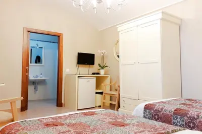 a bedroom with two beds and a desk with a television at Posada Alegria in Medina Sidonia