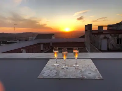two wine glasses on a table on a balcony with the sunset at Posada Alegria in Medina Sidonia