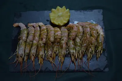 a group of wrapped shrimp on a cutting board with a lemon at Pensión San Marcos in Arcos de la Frontera