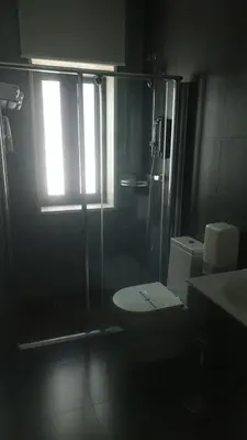 a bathroom with a shower and a toilet and a window at Hotel Los Nardos in Chipiona