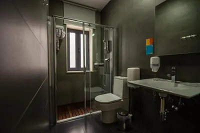 a bathroom with a toilet and a shower and a sink at Hotel Los Nardos in Chipiona