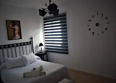 a bedroom with a bed with a clock on the wall at Downtown house centro histórico in Arcos de la Frontera