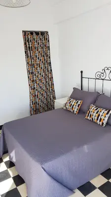 a bed with purple sheets and pillows in a room at Apartamento centro histórico Arcos in Arcos de la Frontera