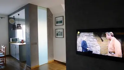 a living room with a flat screen tv on a wall at Precioso duplex con piscina en Real de la Barrosa in Chiclana de la Frontera