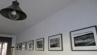a row of pictures on a wall with a light at Precioso duplex con piscina en Real de la Barrosa in Chiclana de la Frontera