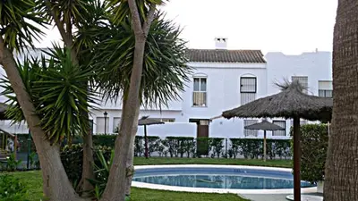 a swimming pool in front of a white building at Precioso duplex con piscina en Real de la Barrosa in Chiclana de la Frontera