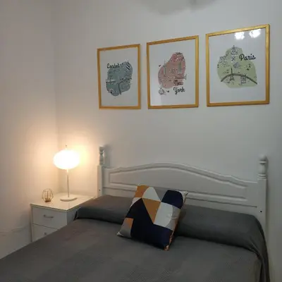 a bedroom with a bed and three pictures on the wall at Apartamento Julieta in Sanlúcar de Barrameda