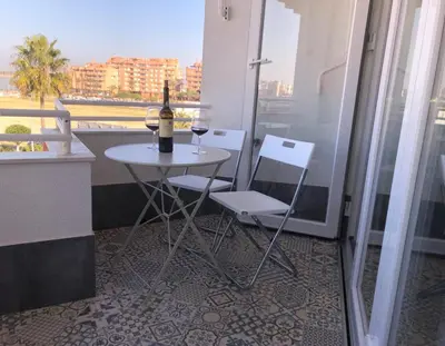 a table with a bottle of wine and two chairs on a balcony at Avenida de las Piletas in Sanlúcar de Barrameda