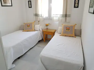 two beds in a small room with a table at Novo Paradise in Chiclana de la Frontera