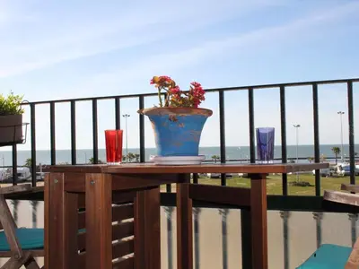 a table with a vase and three glasses on a balcony at Cosy apartment with sea view in Chipiona - 50 m² in Chipiona