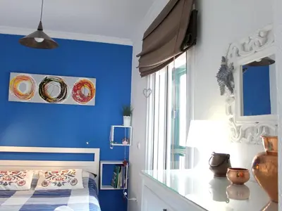 a bedroom with a blue wall with a bed and a table at Cosy apartment with sea view in Chipiona - 50 m² in Chipiona