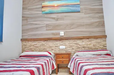 a room with two beds and a painting on the wall at Bungalow La Roa II in Conil de la Frontera