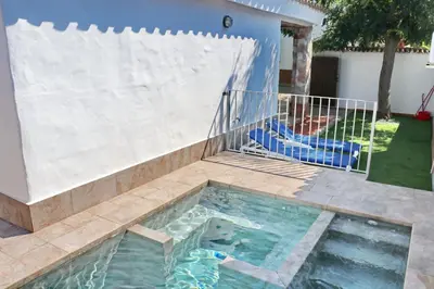 a swimming pool with a fence next to a house at Bungalow La Roa II in Conil de la Frontera