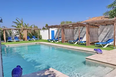 a swimming pool with blue chairs and a resort at Bungalow La Roa II in Conil de la Frontera