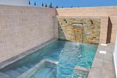 a swimming pool in a brick wall with blue water at Bungalow La Roa II in Conil de la Frontera