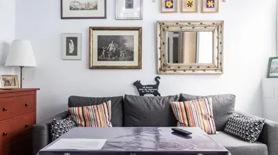 a living room with a gray couch and a mirror at El parador de la artesana in Cádiz
