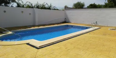 a swimming pool in a yard with a white wall at Alojamiento rural 
