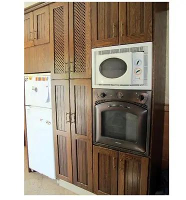 a kitchen with wooden cabinets and a microwave and a refrigerator at Alojamiento rural 