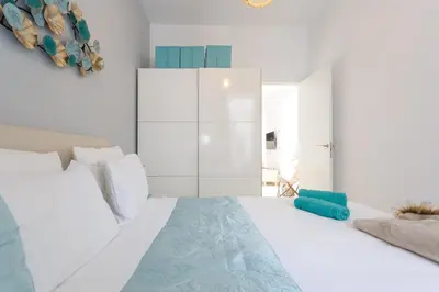 a white bedroom with a large bed and a white cabinet at Mi Bohemia Caleta in Cádiz