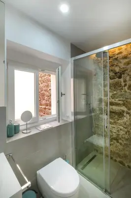 a bathroom with a toilet and a glass shower at Casa La Muralla MEDIEVAL by Cadiz4Rentals in Cádiz