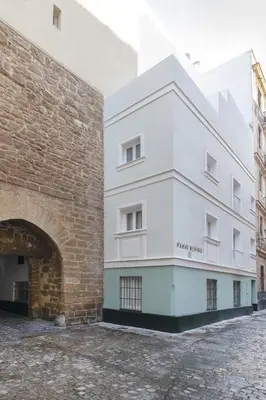 a white building next to a brick wall at Casa La Muralla MEDIEVAL by Cadiz4Rentals in Cádiz