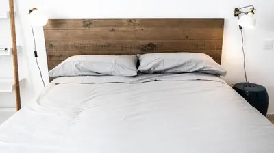 a bed with a wooden headboard and two white pillows at Apartamento Cadiz Paradiso in Cádiz