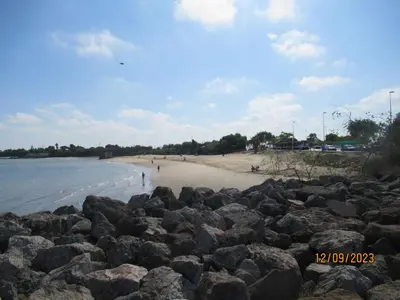 a beach with rocks and people walking on the beach at Apartamento La Gaviota in Chipiona