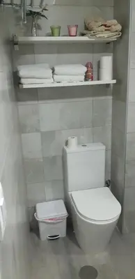a bathroom with a toilet and a shelf with towels at Apartamento La Gaviota in Chipiona